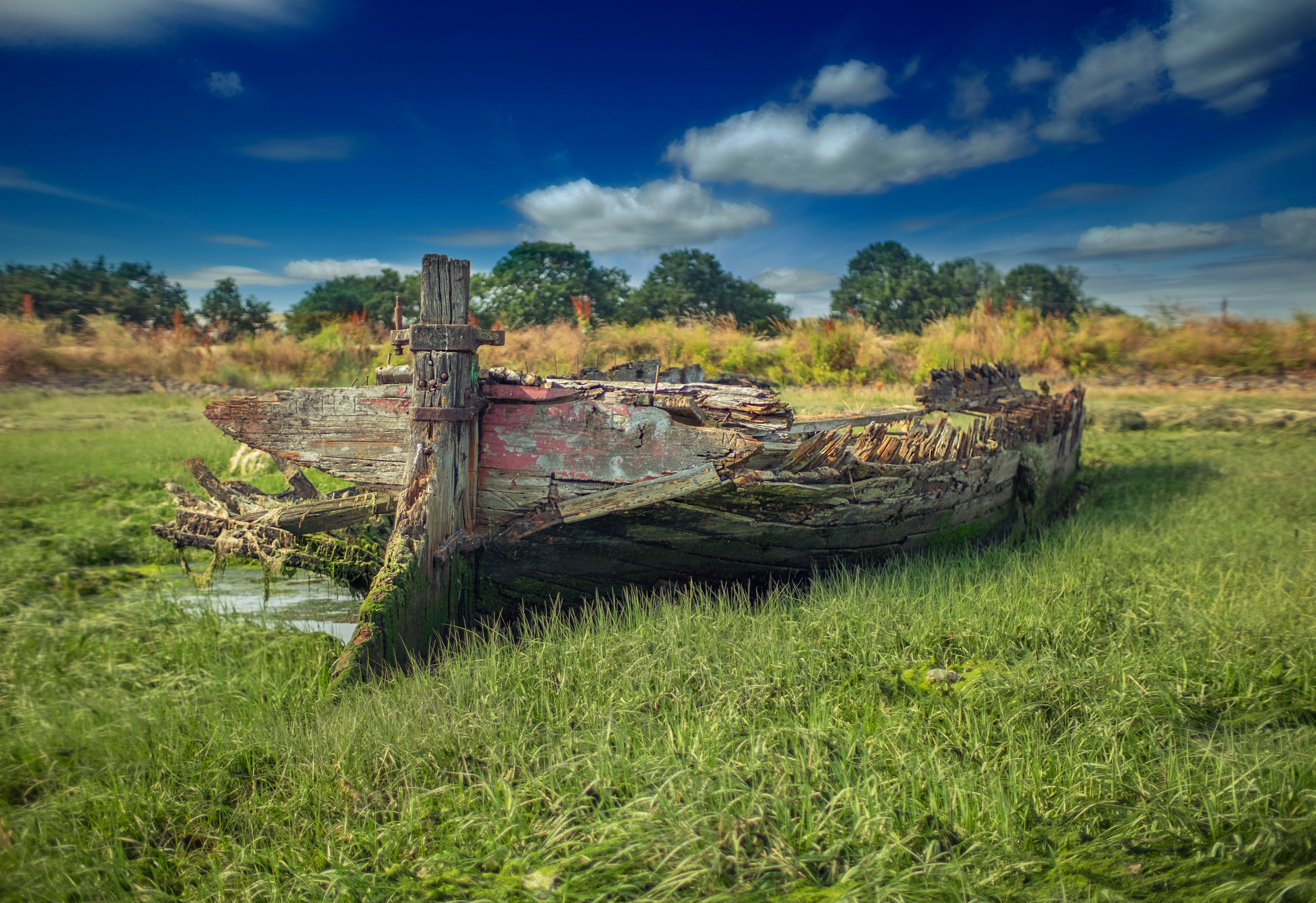 wrecked wooden boat on grass